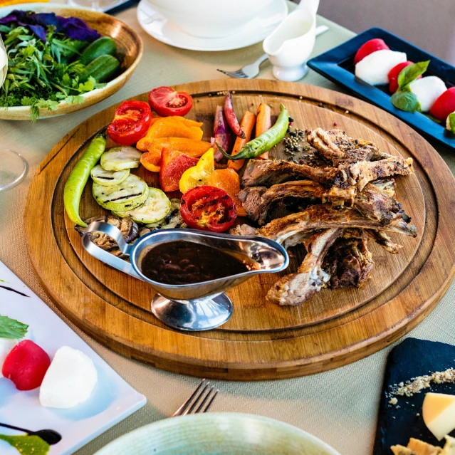 a tray of meat, veggies and salad on a dining table