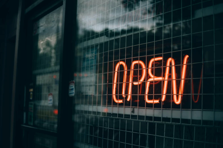 a neon sign in a store window that says open