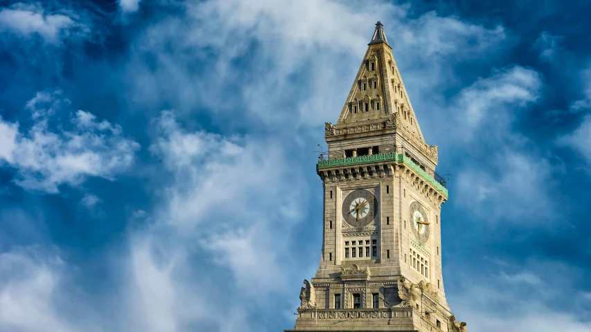 large clock tower on cloudy blue sky with clouds