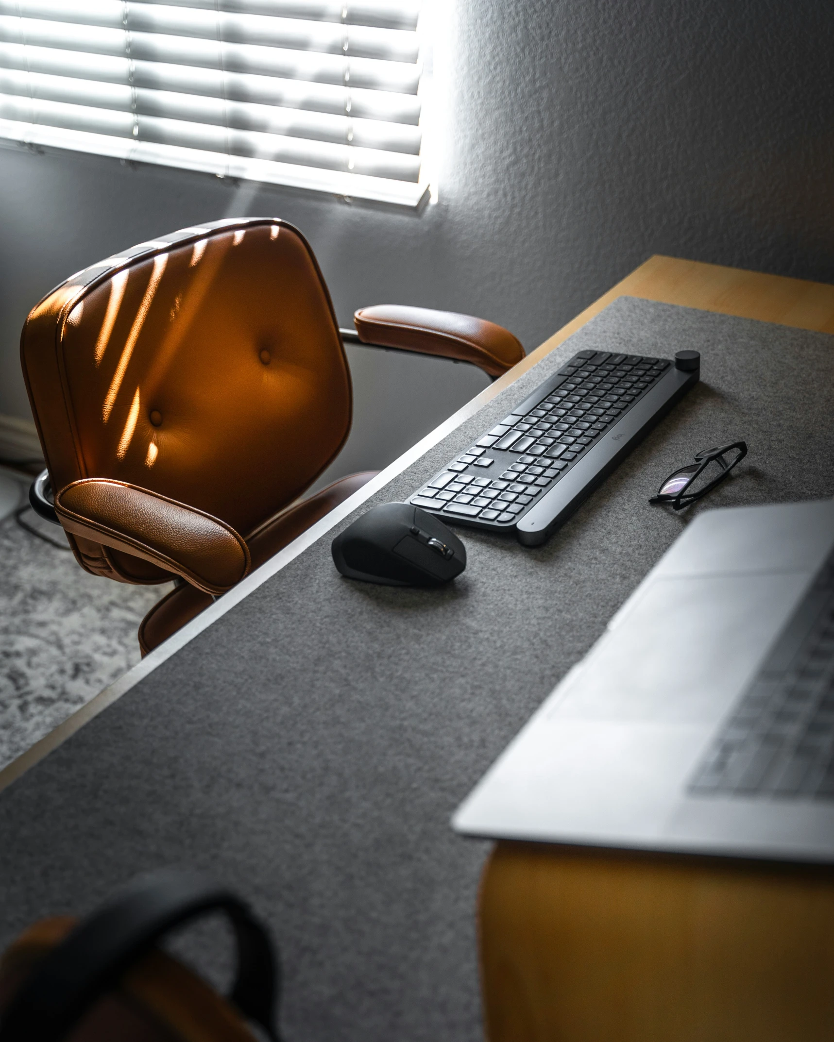 an office desk with laptop, monitor and chair