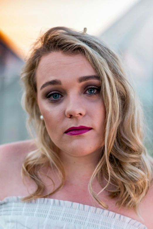 a woman wearing blue eyes, pink lipstick, and white top