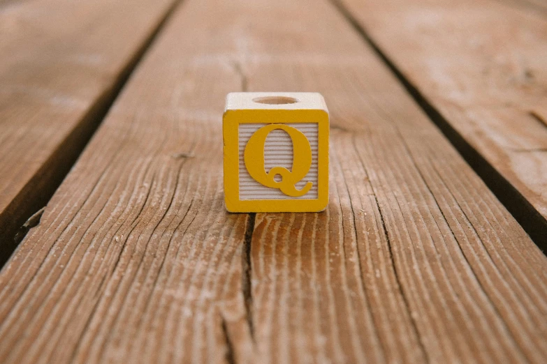 a wooden alphabet block with the letter q