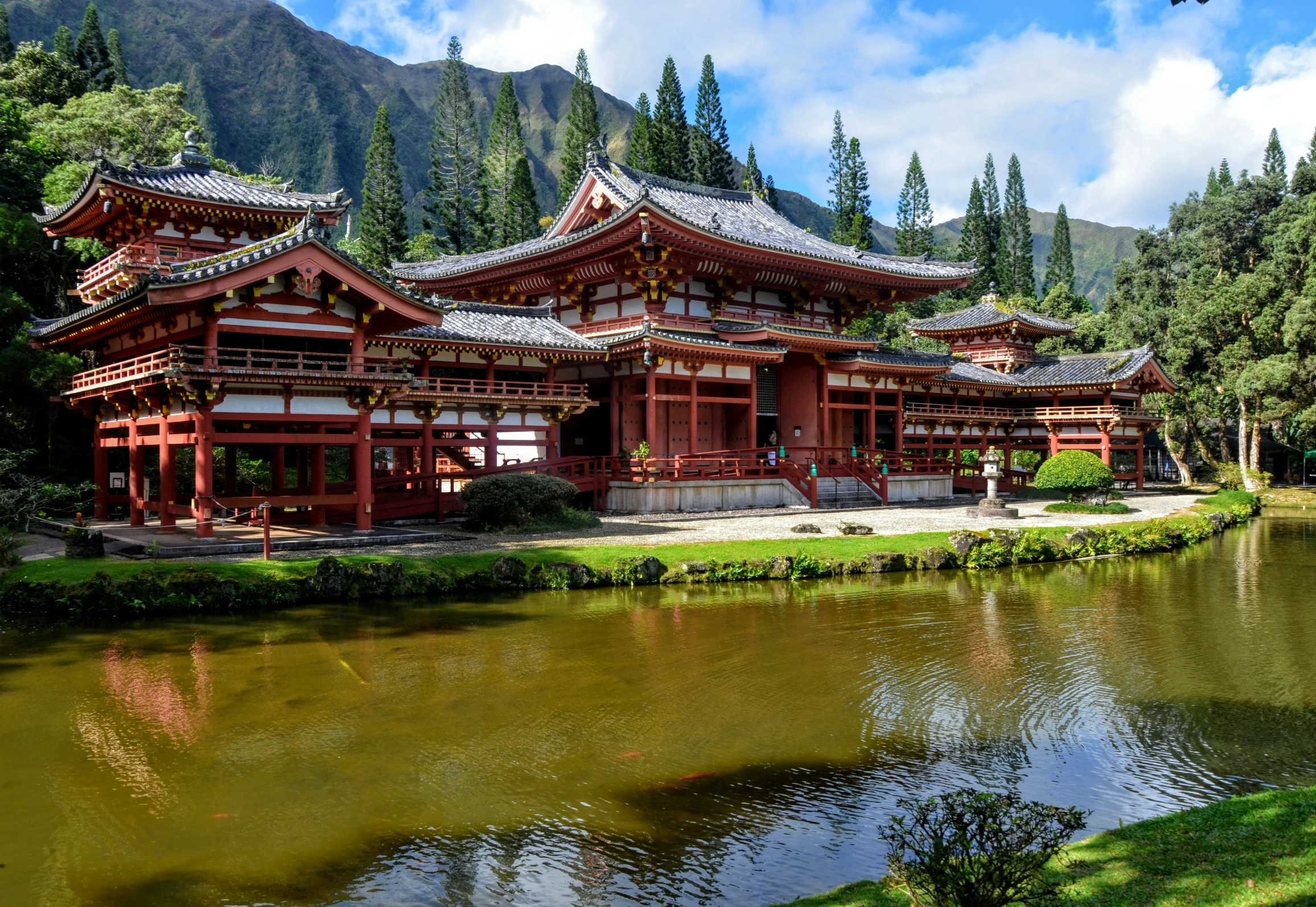 oriental style building next to small lake with pine trees