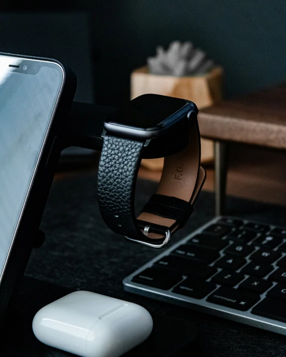 a smart watch on a leather wristband, in front of an open laptop