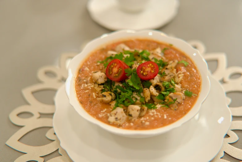 a bowl of soup with some tomatoes and vegetables on it