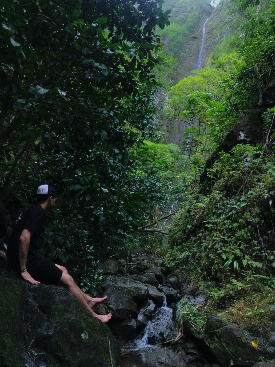 a man that is sitting on a rock