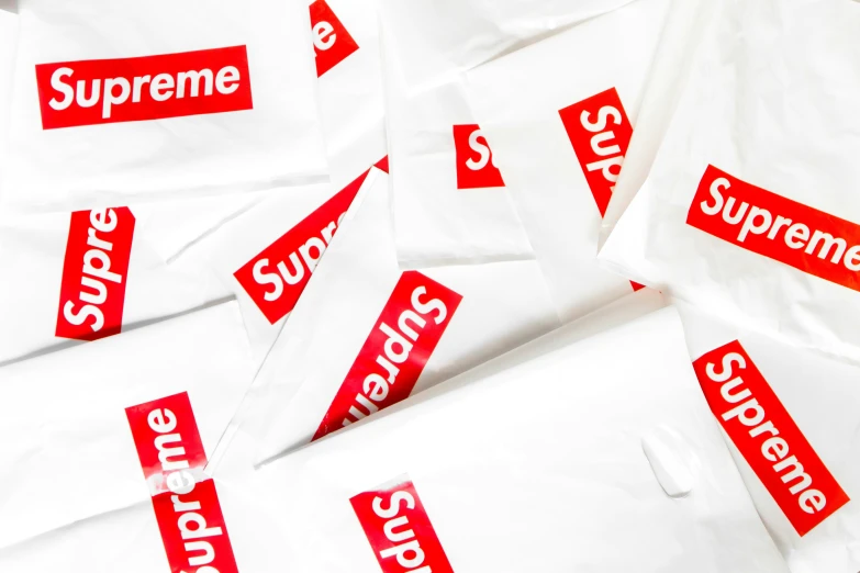 red supreme stickers on white bags laying next to each other