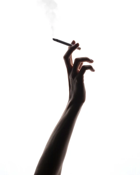 a persons arm holding a cigarette with smoke coming out