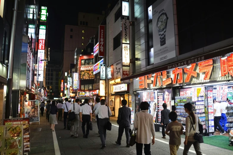 a crowded street at night with a lot of people walking around