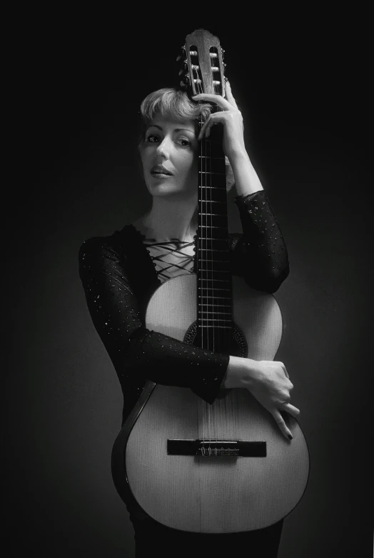 a woman holds her guitar while she wears a black top