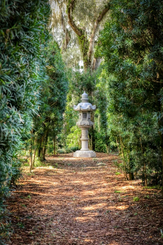 a stone monument nestled amongst trees at the end of a dirt path