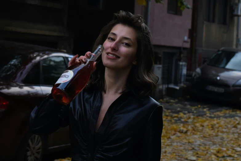 woman in leather jacket holding up a drink