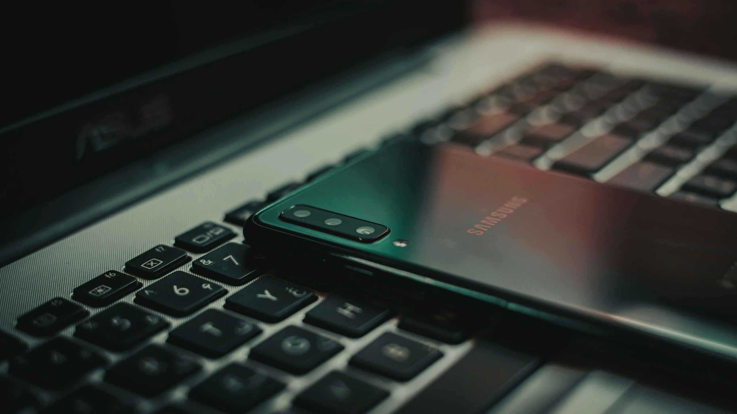 this is a cellphone and keyboard on top of a laptop