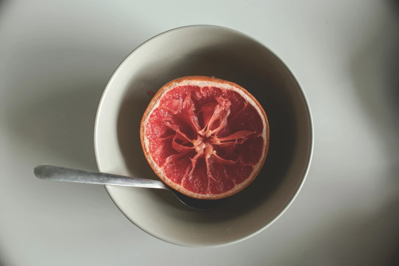 a  orange sitting in a bowl with a spoon