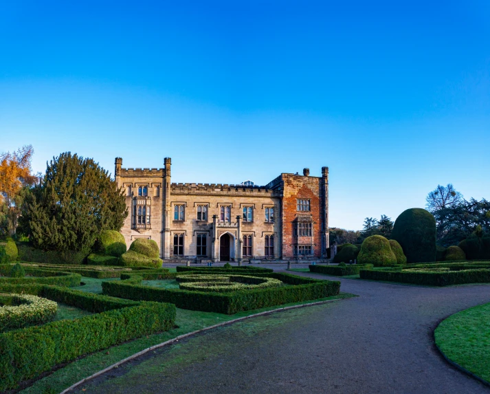 a large stone building with many trimmed hedges around it