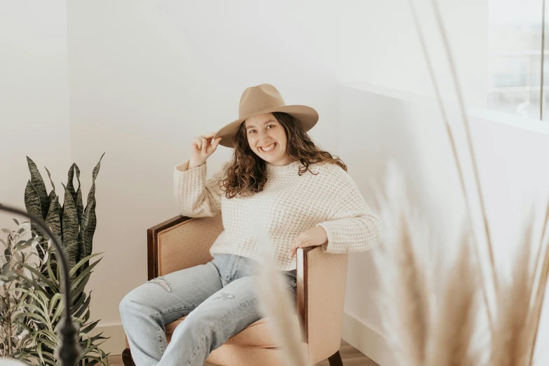 a woman wearing a hat, sitting in a chair