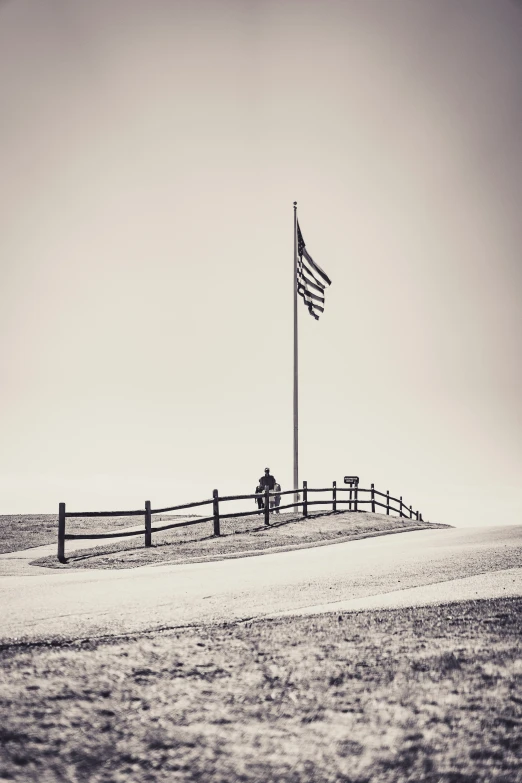 a beach with a fence and a flag pole