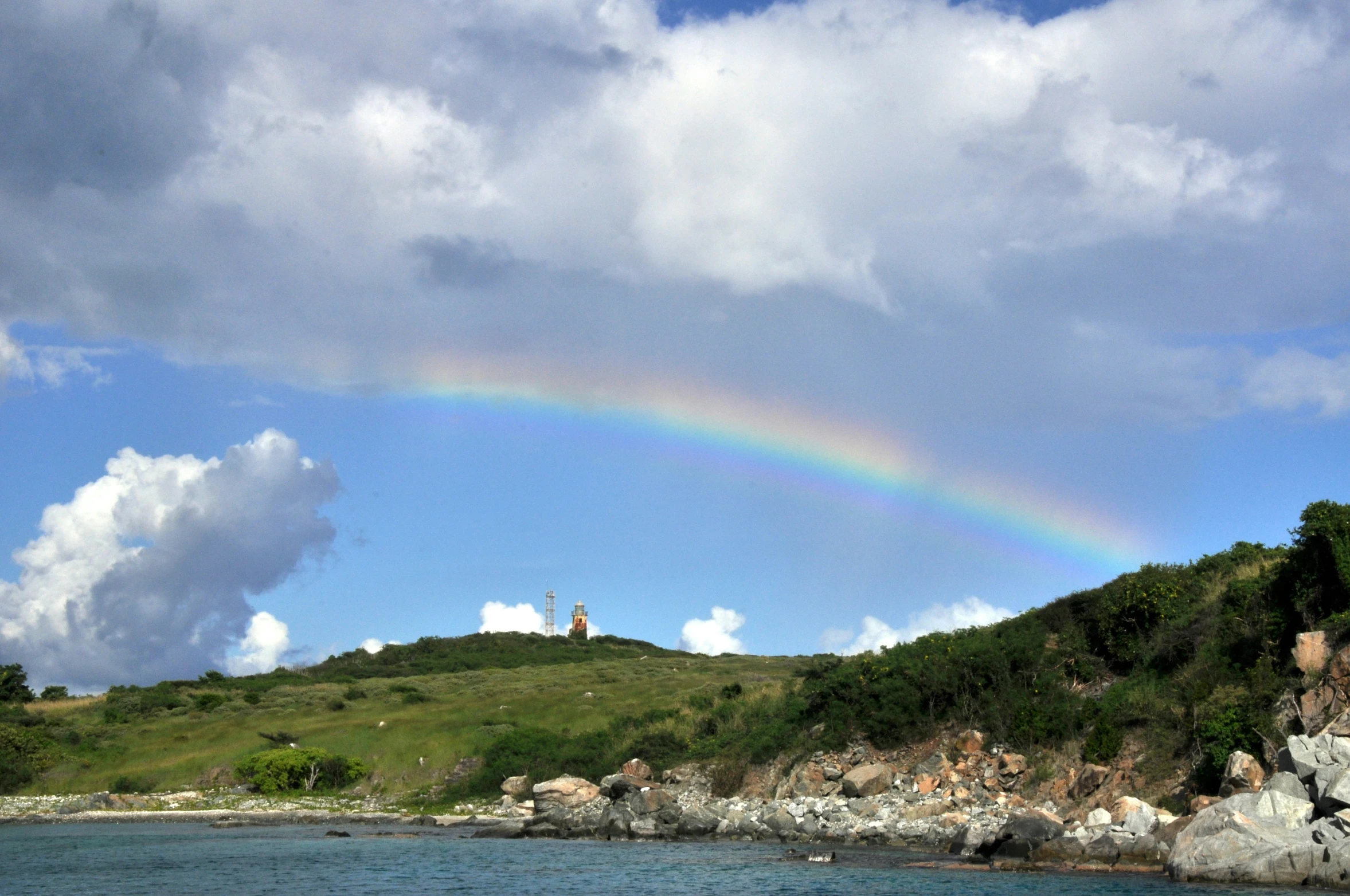 a rainbow appears over the top of the hill