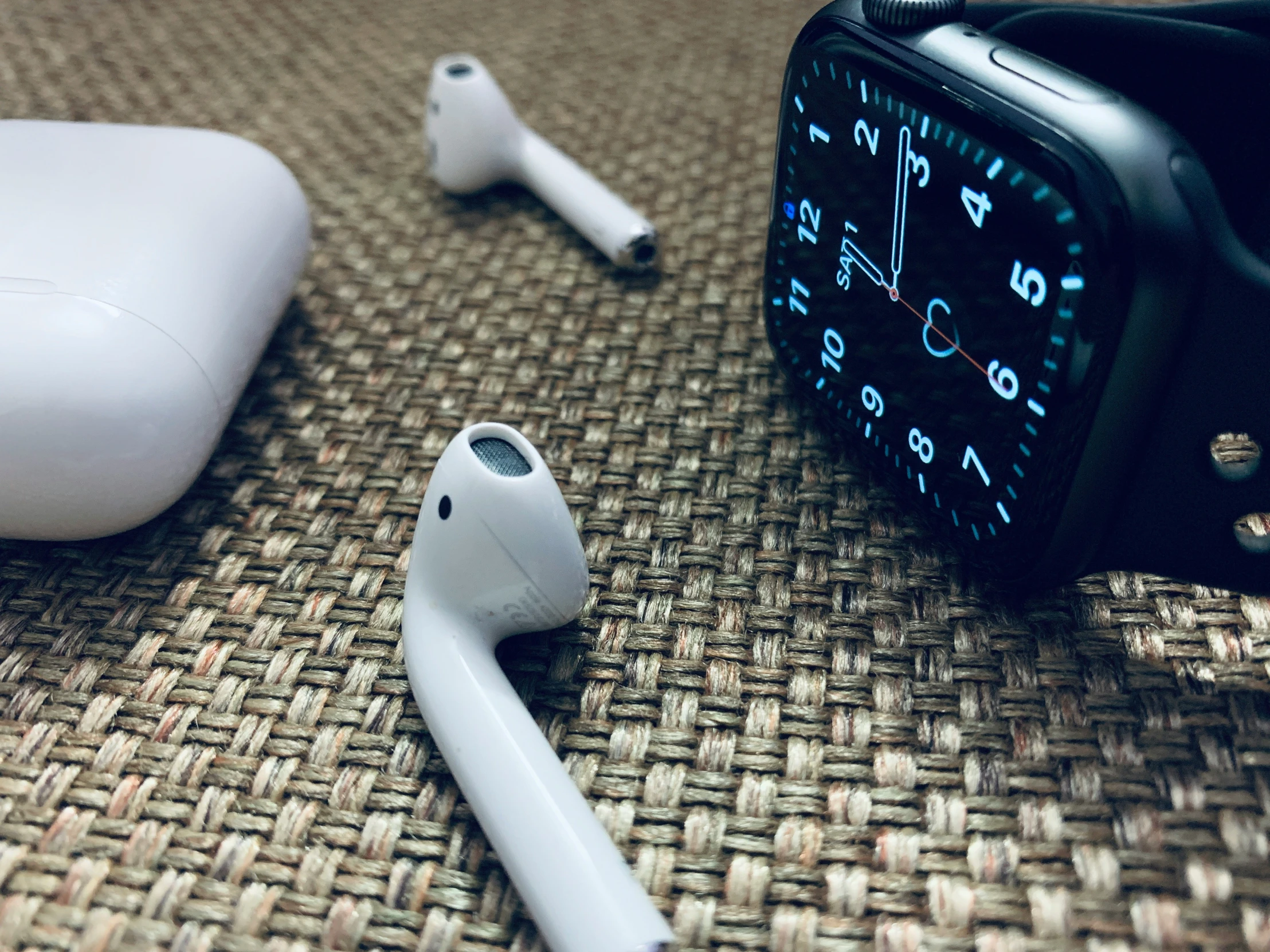 a watch, phone earphones and an ipod watch on a table