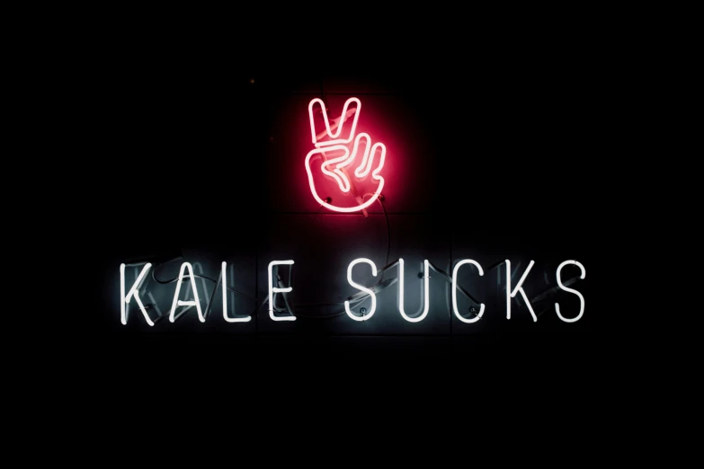 a neon sign that reads kale sucks over it