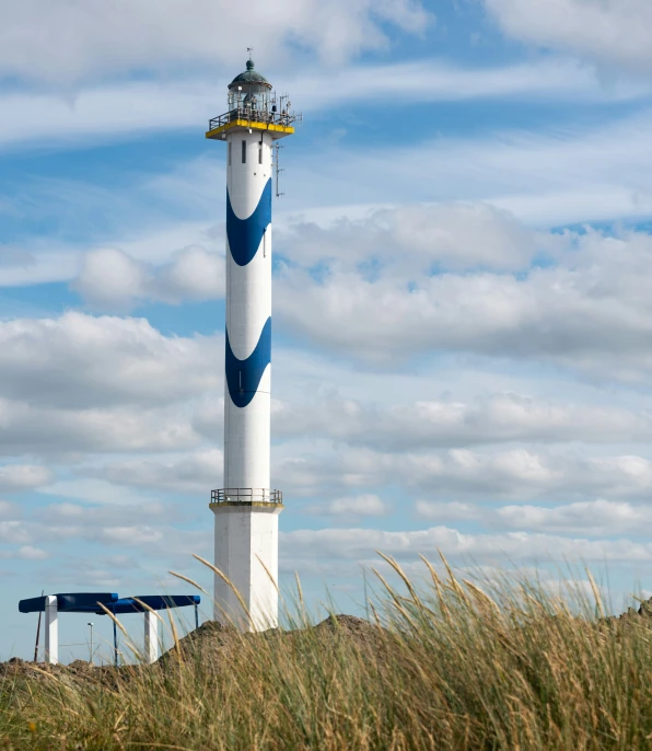 the tall lighthouse is next to some green grass