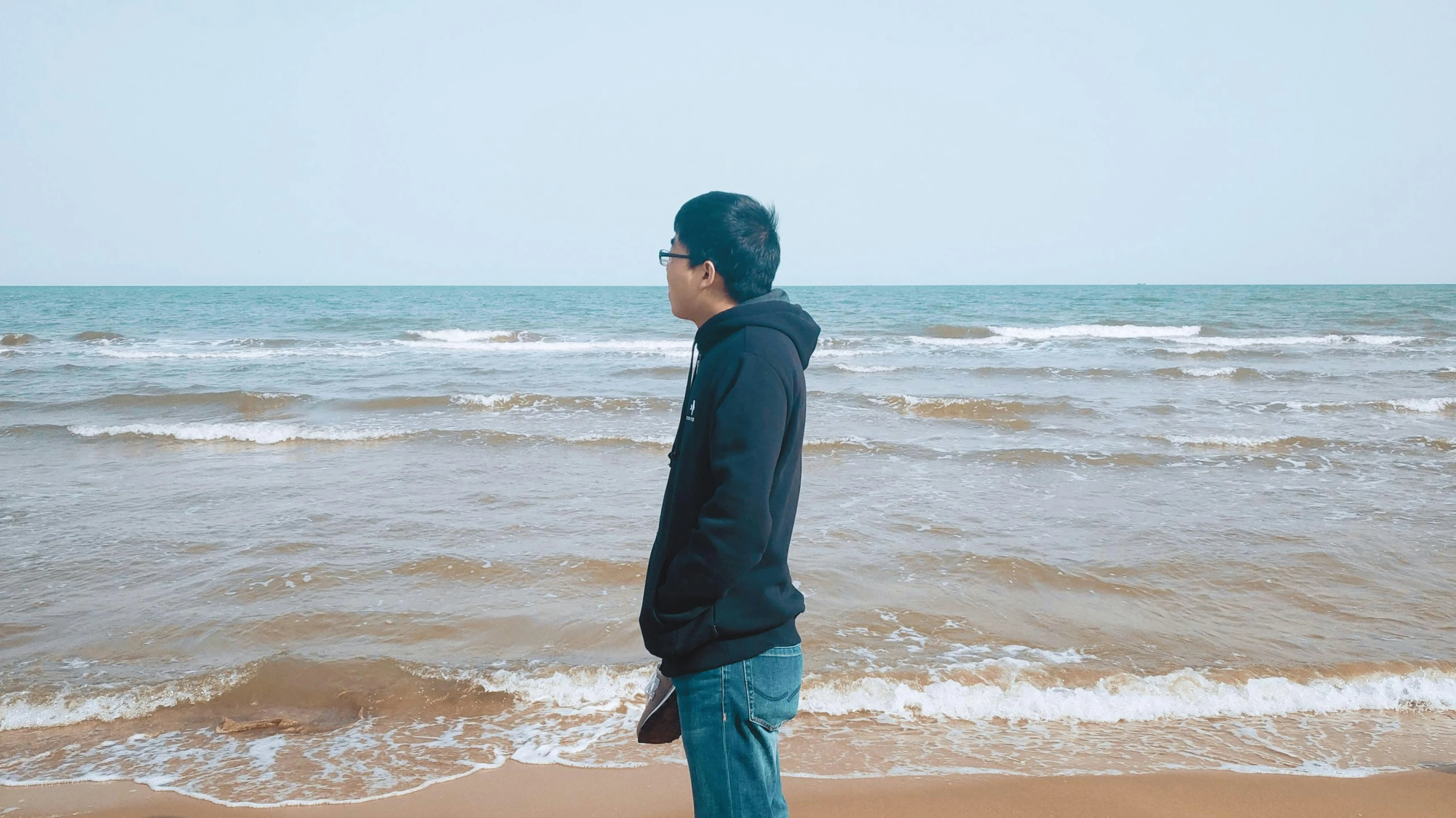 there is a man standing on the beach looking out at the water