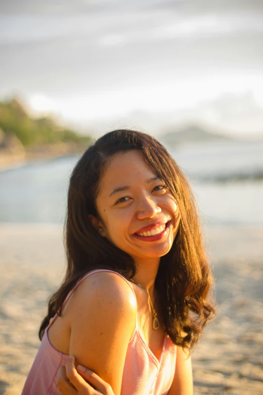 a girl is smiling while sitting on the beach