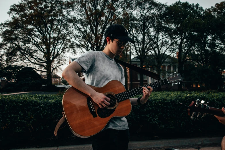 a man plays his guitar on the sidewalk