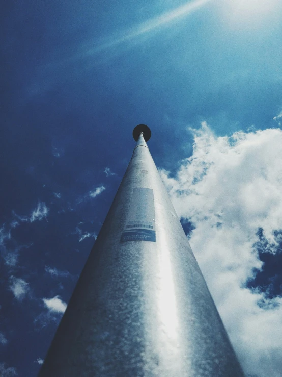 looking up at the tall metal cone that is standing out in the sky