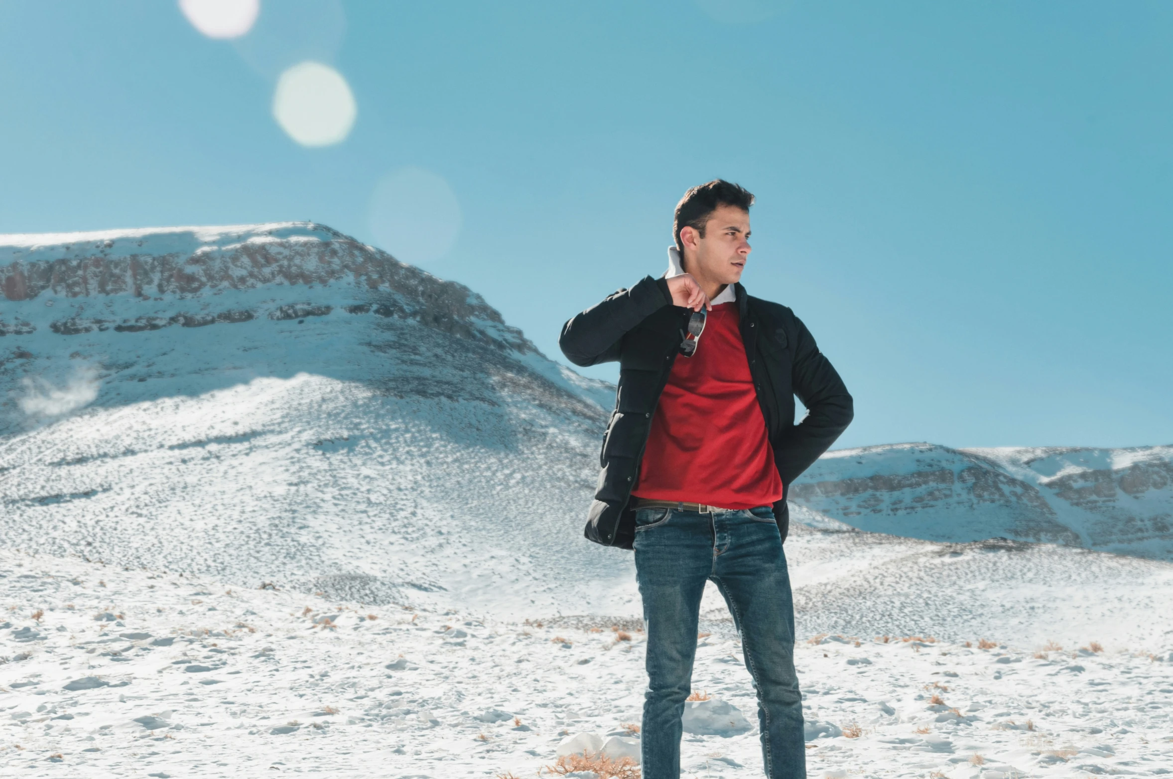 a man in a red sweater and black jacket talking on his phone