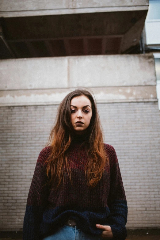 a woman standing in front of a building and looking at the camera