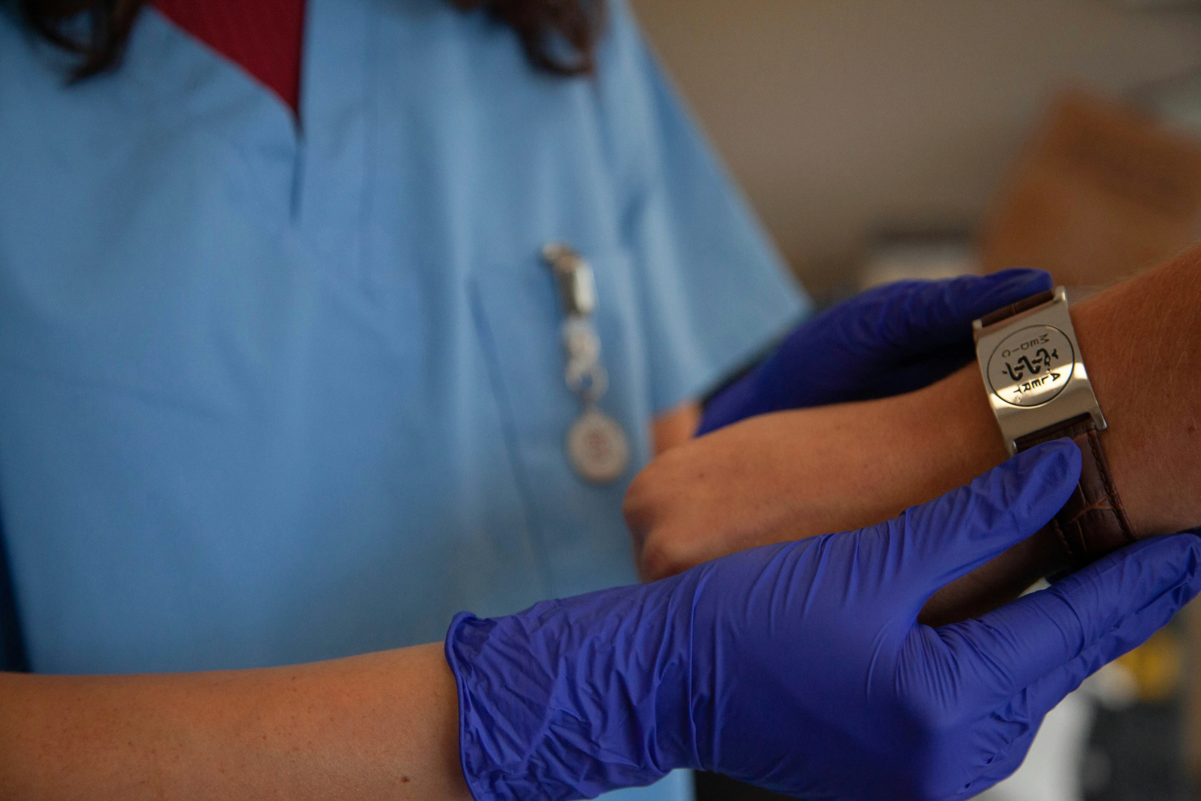 a person with a blue glove on holds onto another persons wrist