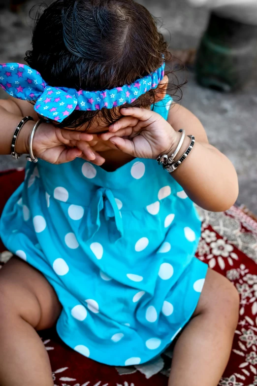 small child sits and covers her eyes with one hand