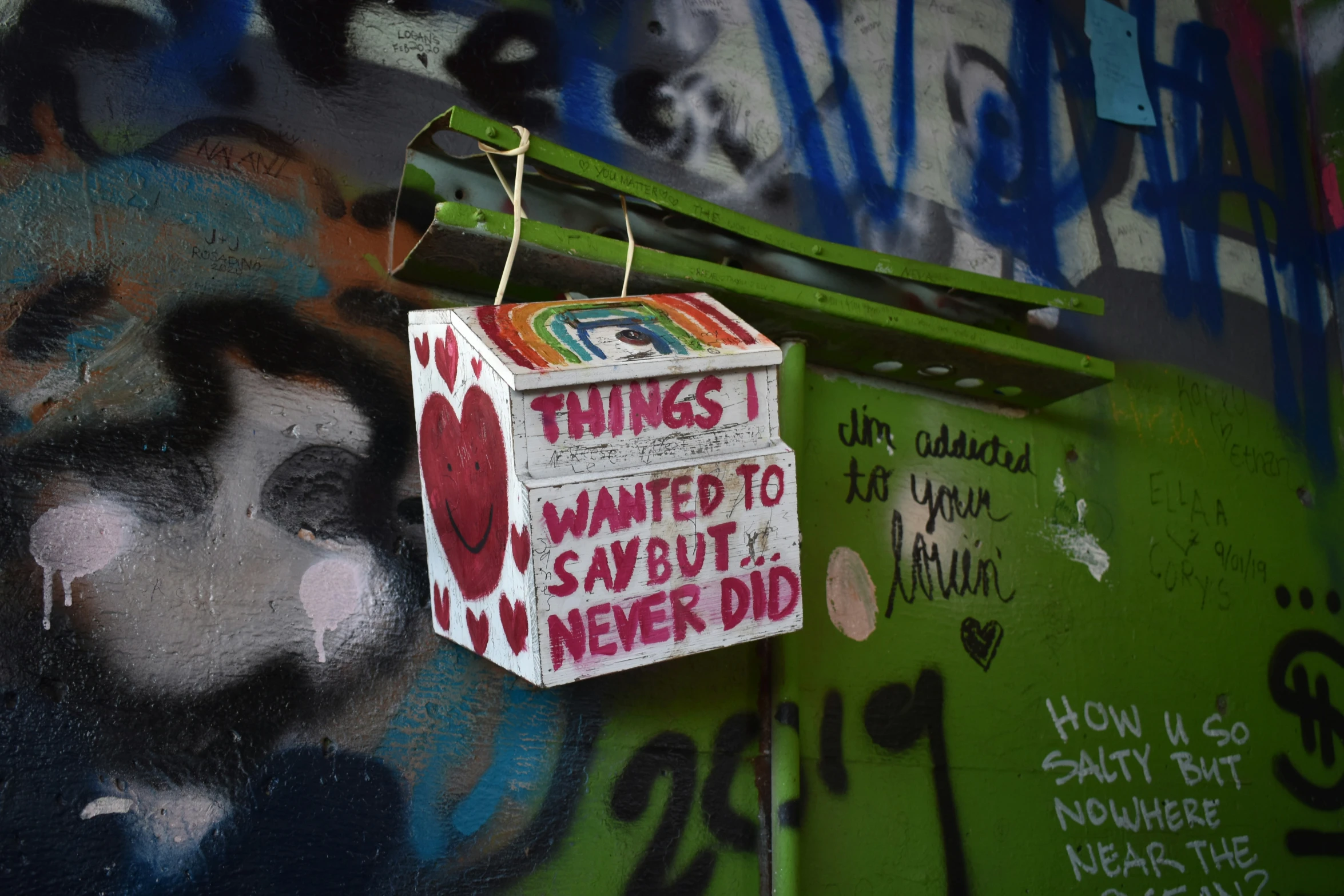 a box is hanging from a graffiti covered wall