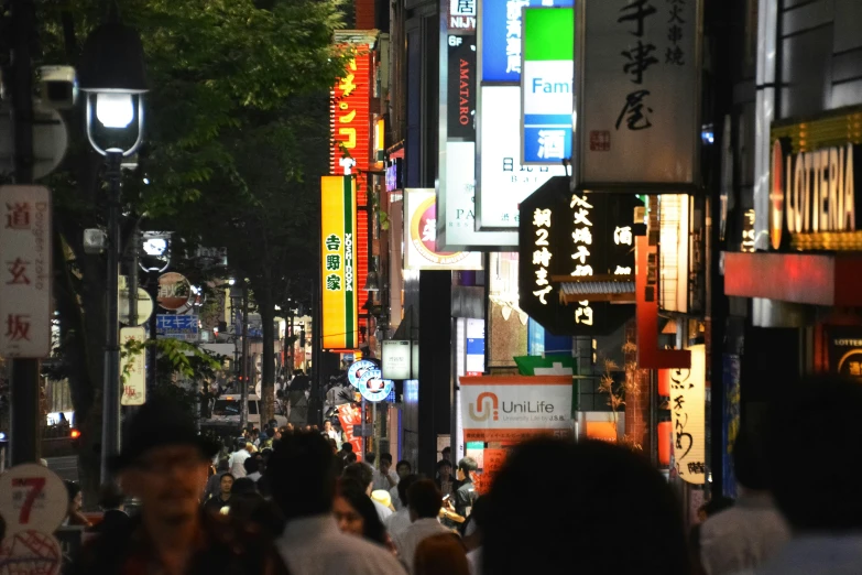 a crowded city street at night with signs and people