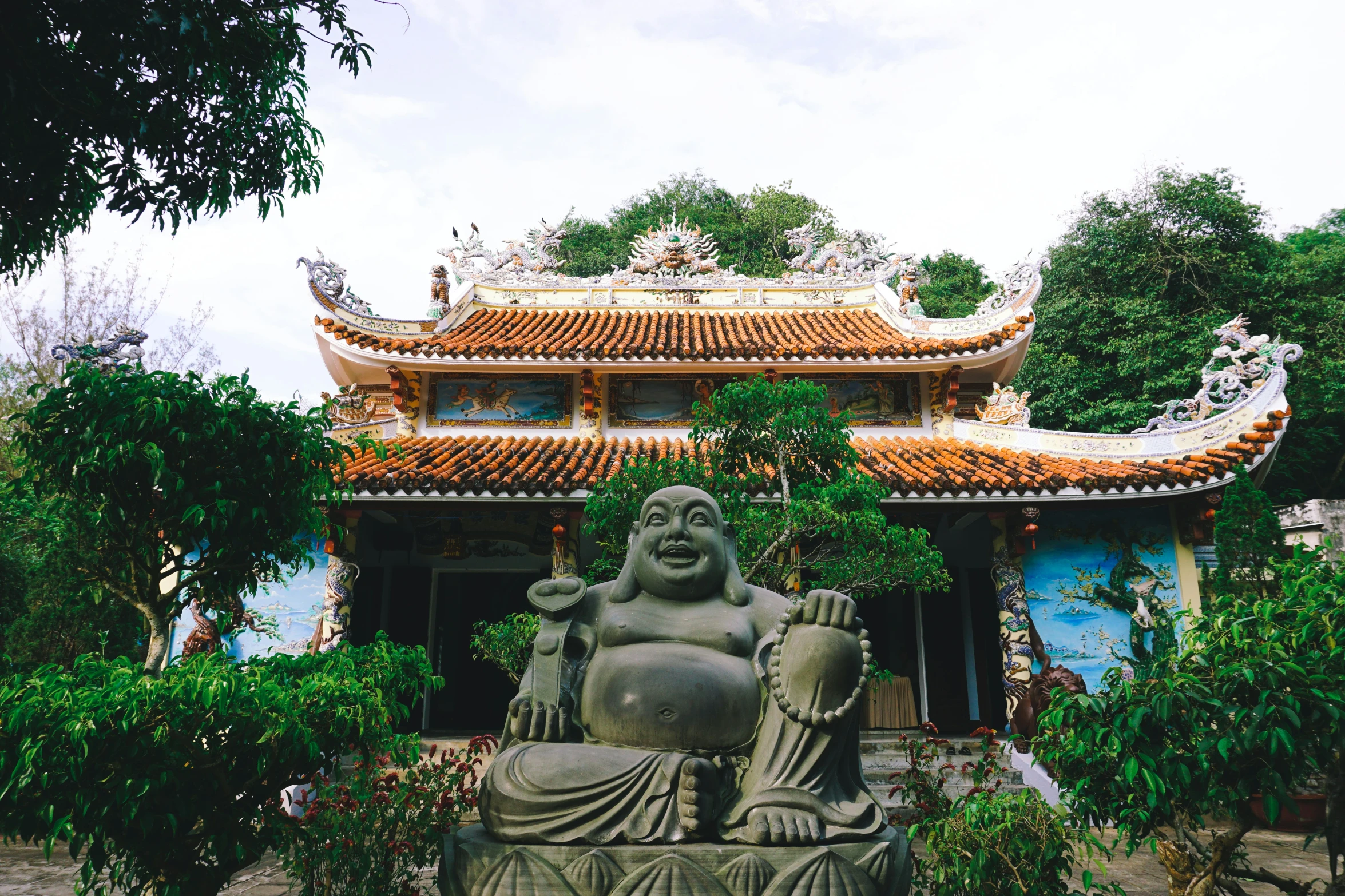 a stone statue of buddha sitting in front of a blue building