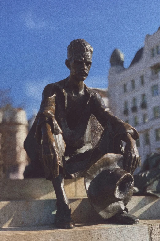 a man sitting on the ground next to a sculpture