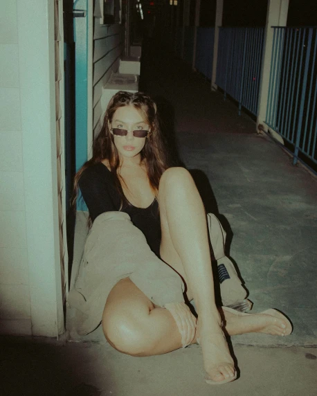 young woman sitting on the sidewalk in black clothing