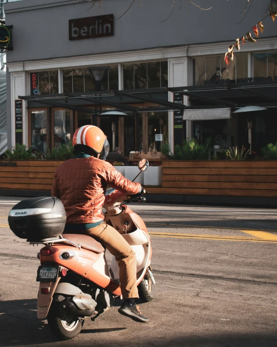 a man riding on the back of an orange motorcycle