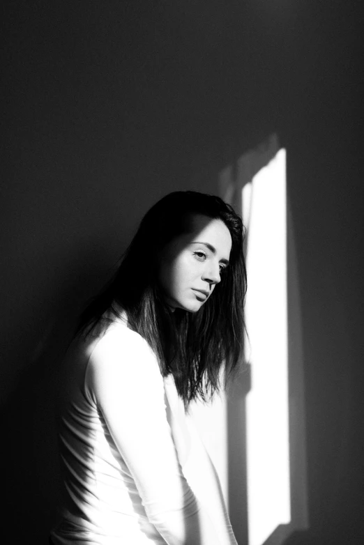 a black and white po of a woman sitting in front of a window