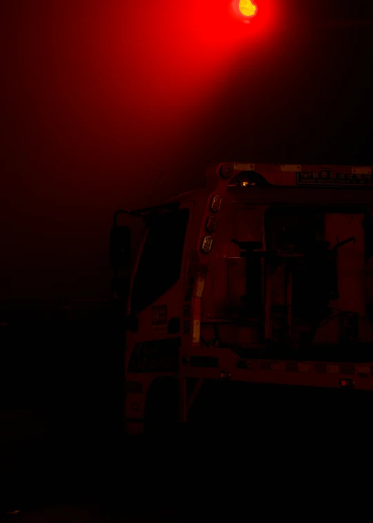 a red stop light shines above a white truck