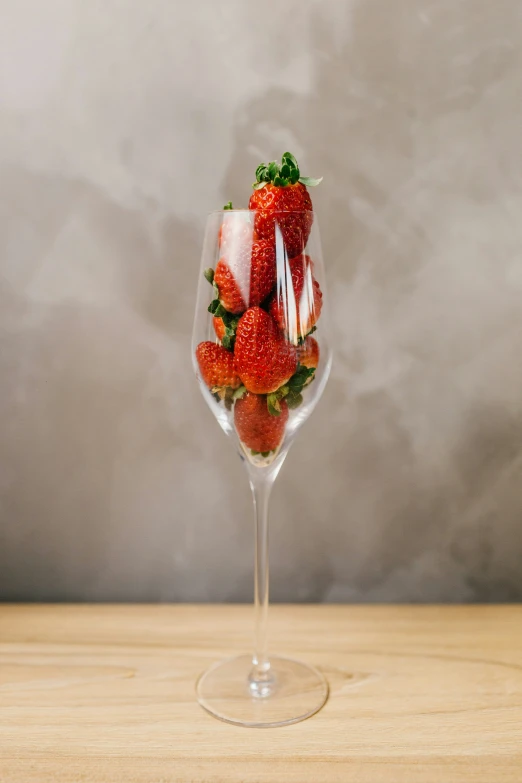 strawberries are in an alcoholic glass with liquid being poured into it