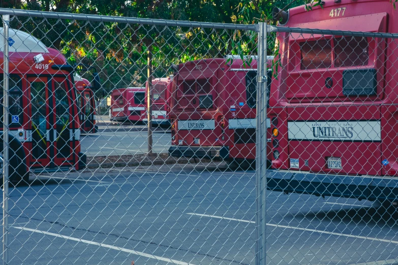 several buses sitting behind a chain link fence