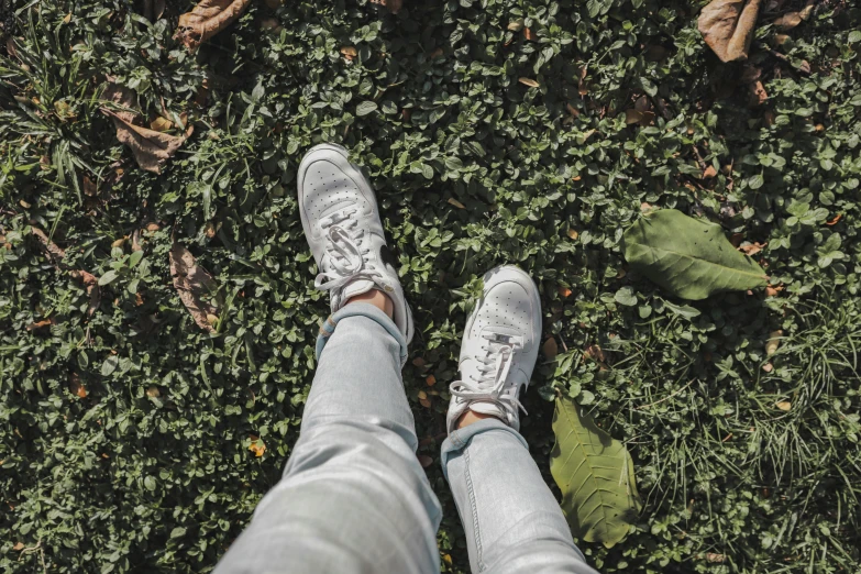 person wearing white shoes standing in grass