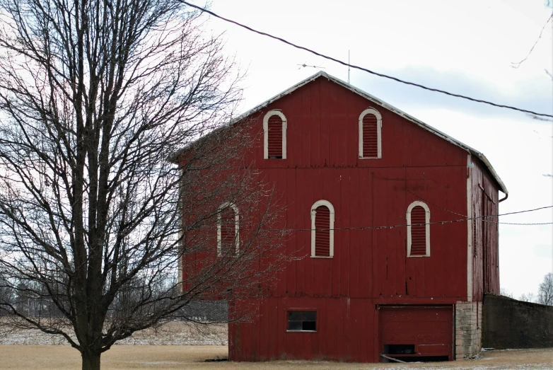 a large red barn with two story windows and a shed next to it