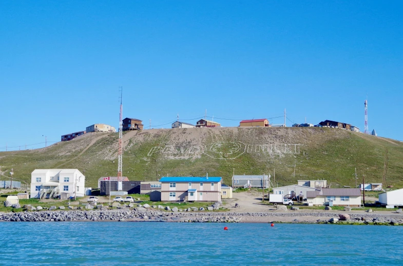 a village sits on the cliff above the water