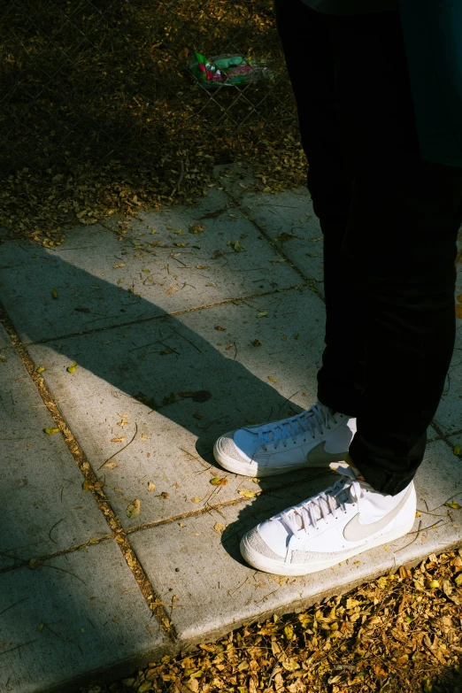 a person standing on the side walk with white shoes on