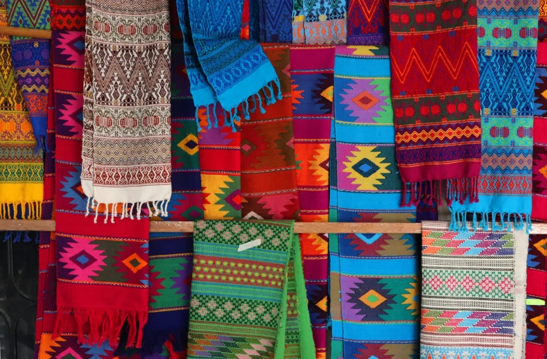 a shelf full of colorful rugs in an open market