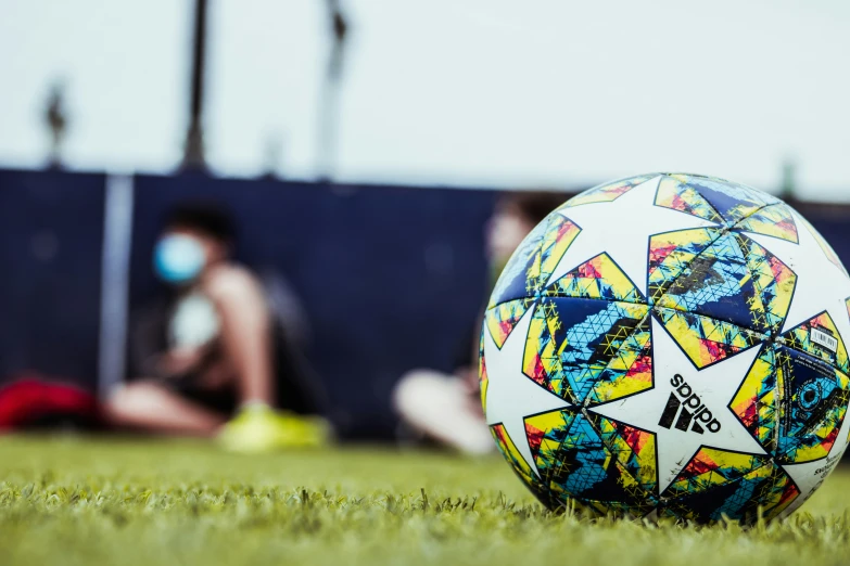 a person sitting in the grass near a large soccer ball