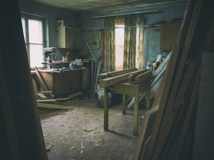 a kitchen is pictured from the doorway way with curtains and the floor is completely damaged